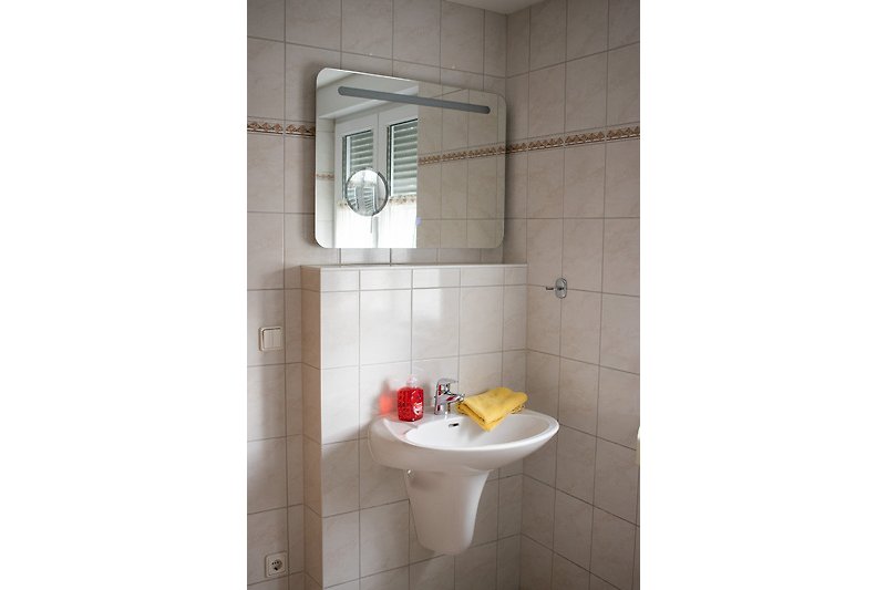 Bad mit Fenster, Handtuchtrockner und beleuchtetem Spiegel