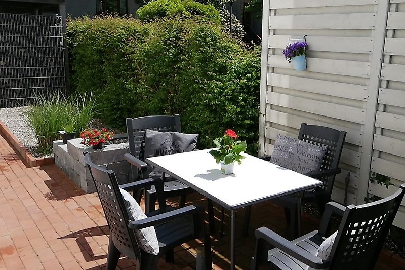 Schöner Garten mit Tisch, Stühlen und Blumen.