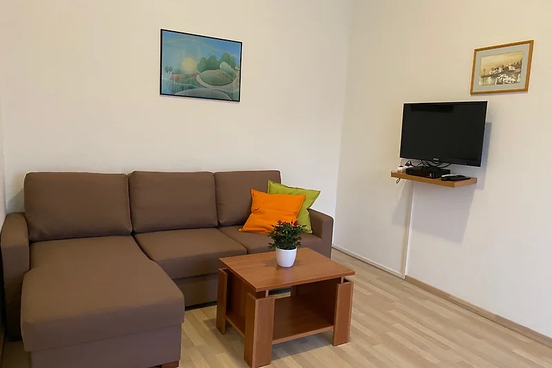 Großzügiger Wohnbereich mit Sofa, Esstisch, TV und stilvollem Holzmobiliar.
