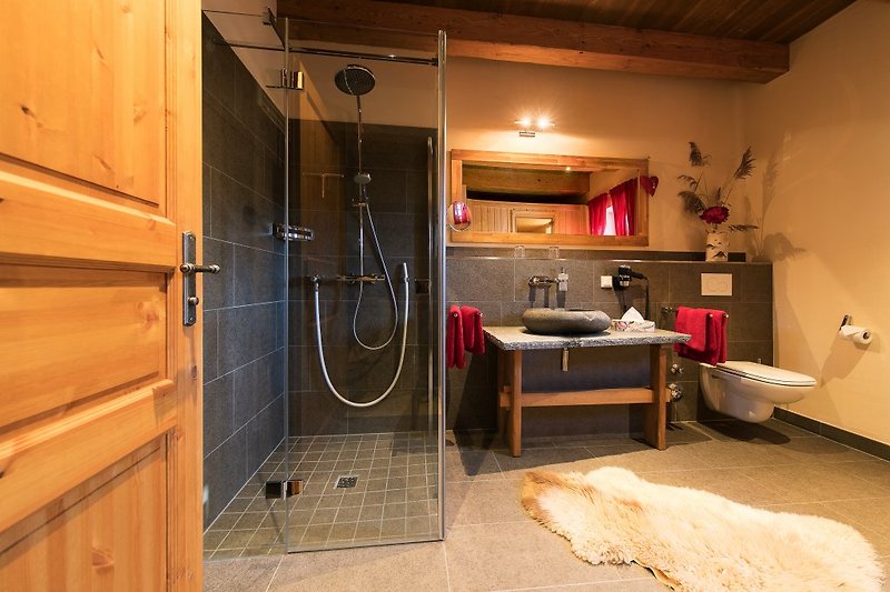 Bad im EG mit Fußbodenheizung, Sauna, Handtuchheizkörper, Natursteinwaschbecken und Regendusche