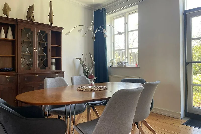 Esszimmer mit großem Tisch, 6 Stühlen und  antikem Holzschrank.