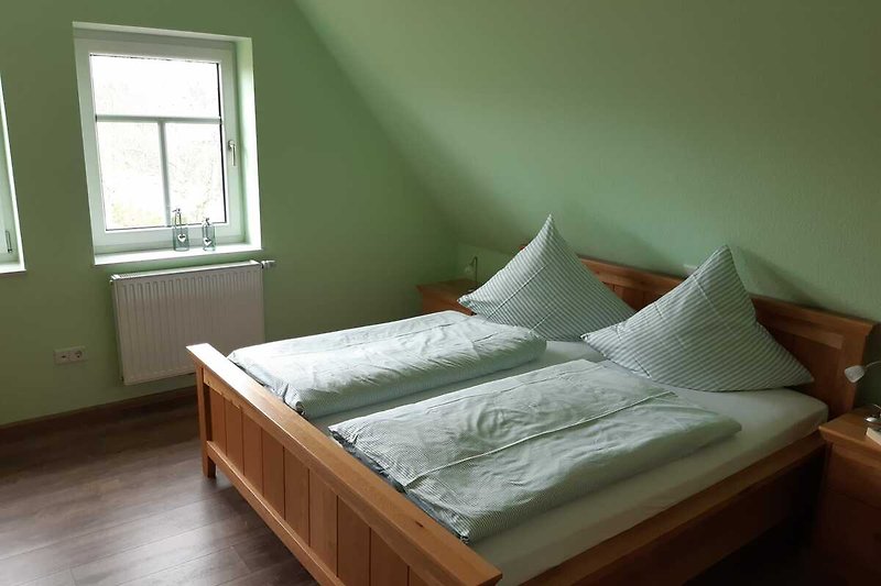Gemütliches Schlafzimmer mit Doppelbett und Fensterblick.