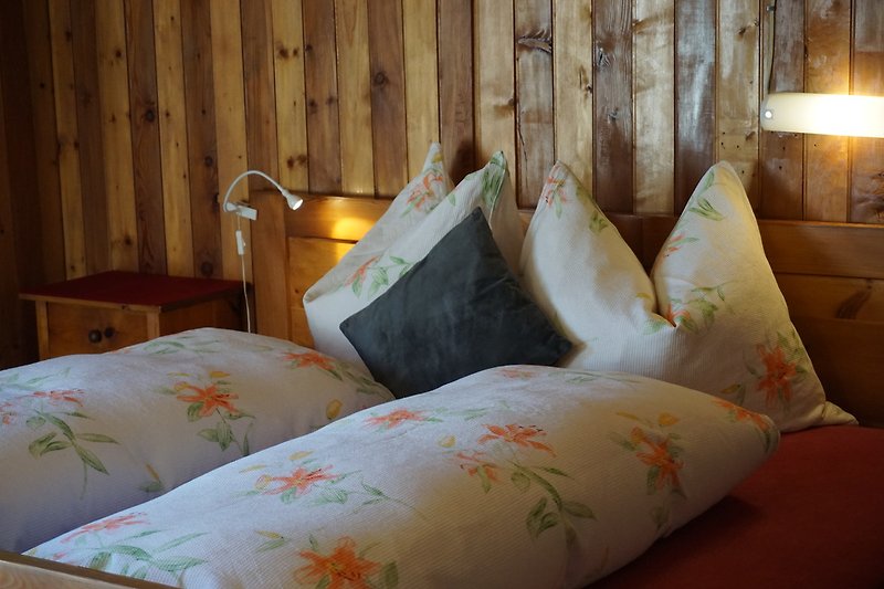 Schlafzimmer mit Holzbett, Lampen und gemütlichen Textilien.