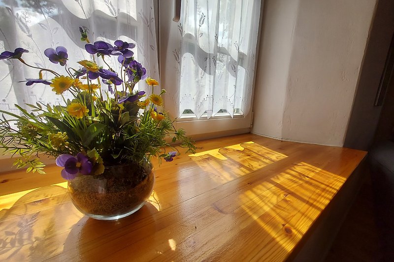 Blumen auf Holzfensterbrett.