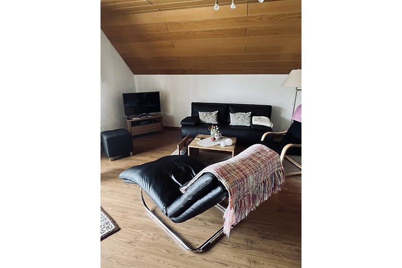 Gemütliches Wohnzimmer mit Holzboden und bequemer Couch.