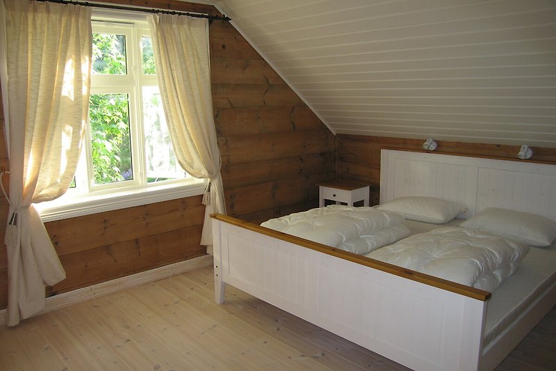 Schlafzimmer mit bequemem Bett und Fenster mit Vorhang.