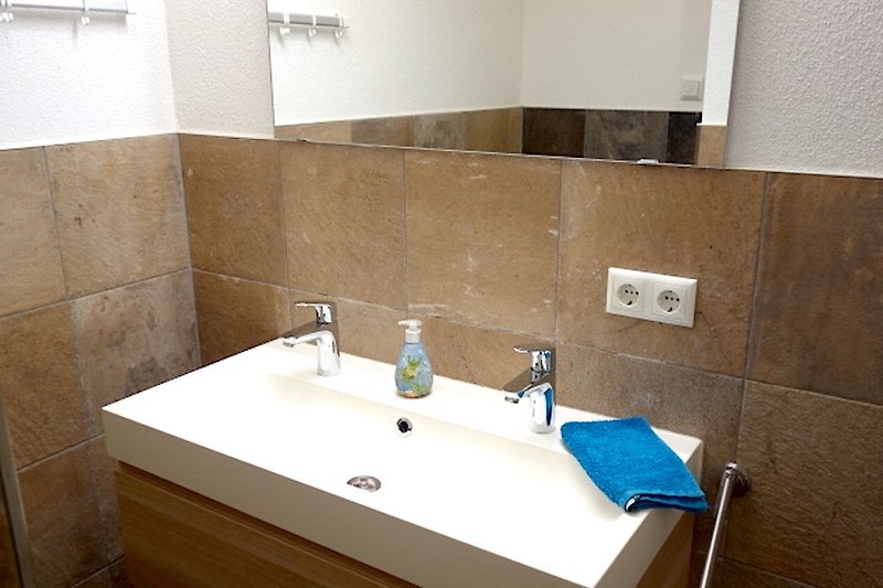 Badezimmer mit Spiegel, braunem Waschbecken und Armatur.