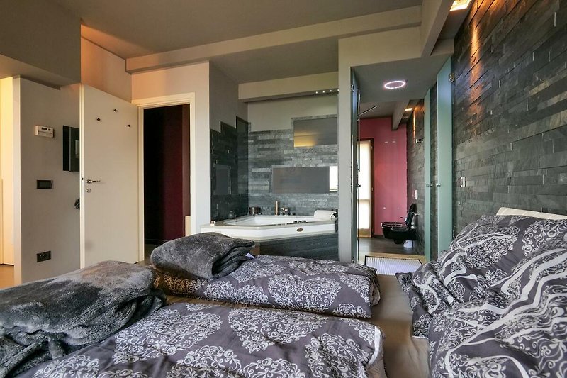 Schlafzimmer mit Doppelbett und integrierter Whirlpoolbadewanne