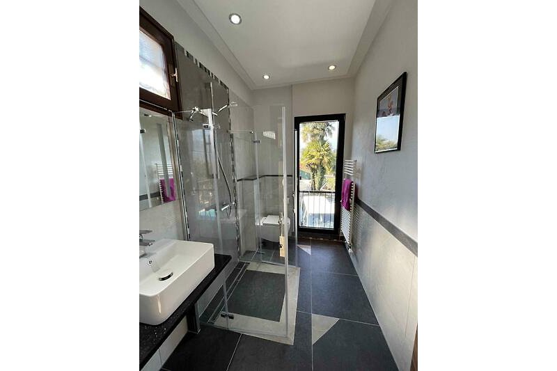 Freundliches Badezimmer mit Dusche, Waschtisch, WC und Fenster