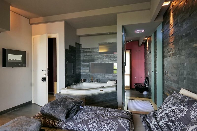 Schlafzimmer mit Doppelbett und integrierter Whirlpoolbadewanne