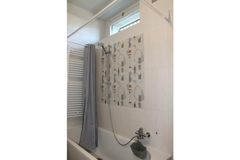 Freundliches modernes Badezimmer mit Badewanne mit Duschmöglichkeit, Bidet, Waschmaschine und Fenster