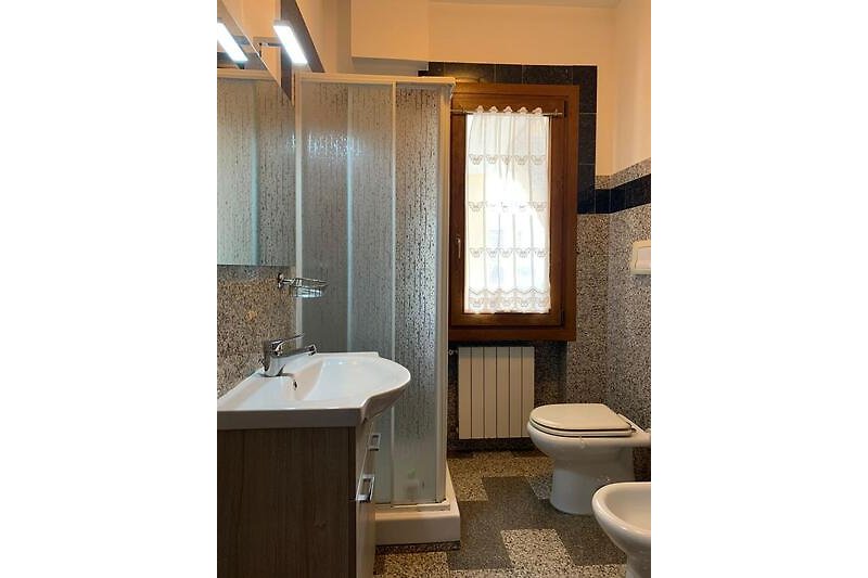 Badezimmer mit Dusche, Bidet, Waschmaschine und Fenster