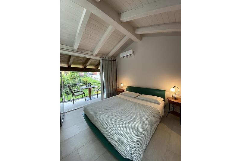 Schlafzimmer mit Doppelbett und Ausgang auf den Balkon