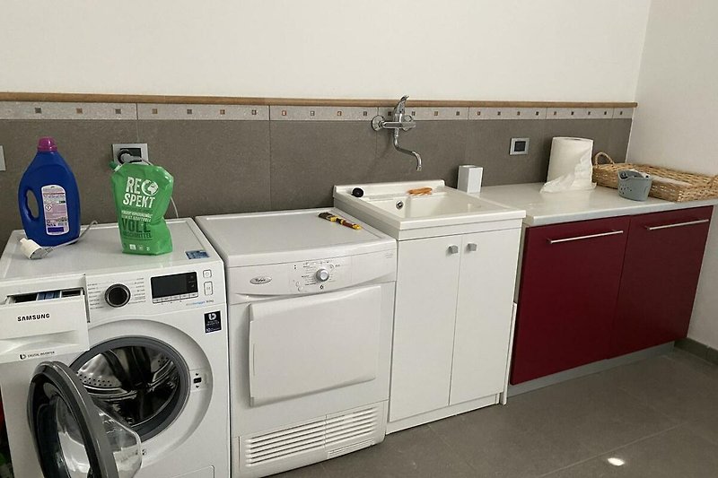 Hauswirtschaftsraum mit Waschmaschine, Trockner, Bügelbrett, Waschbecken
