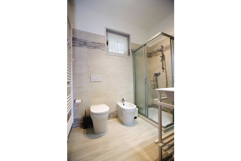 Freundliches und modernes Badezimmer mit Dusche, Bidet und Fenster