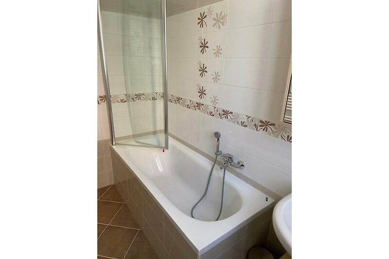 Freundliches Badezimmer mit Badewanne (Duschmöglichkeit) und Fenster