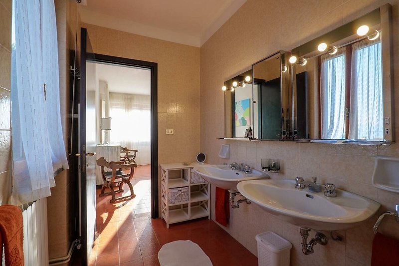 Badezimmer mit Doppelwaschbecken, Dusche, Bidet und Fenster