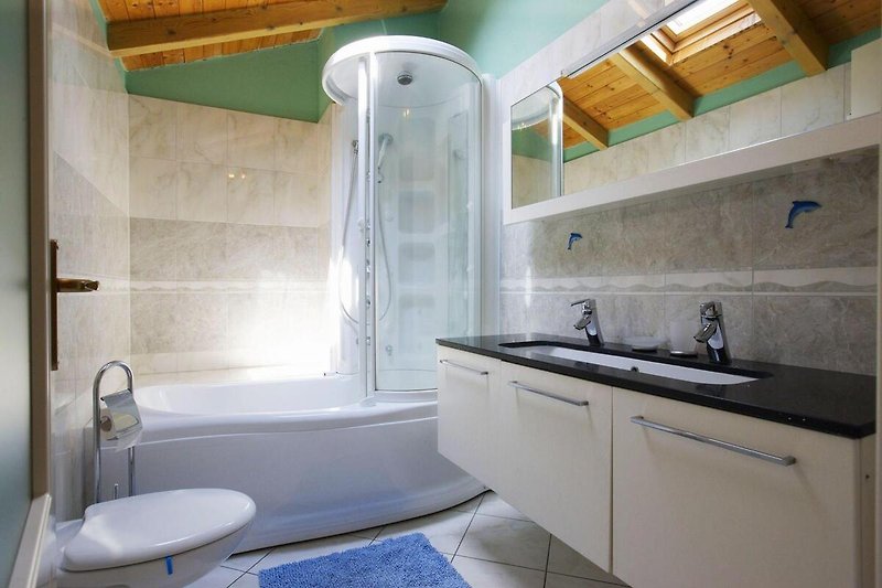 Freundliches, modernes Badezimmer mit Badewanne und integrierter Dusche sowie Fenster