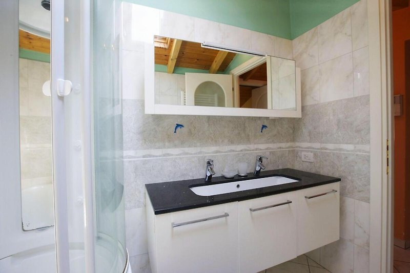 Freundliches, modernes Badezimmer mit Badewanne und integrierter Dusche sowie Fenster