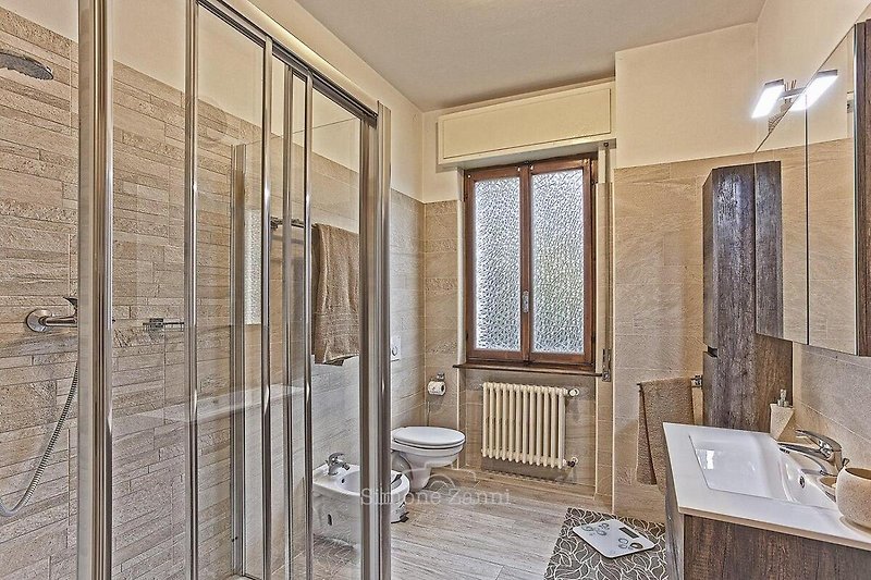 Freundliches, modernes Badezimmer mit großer Dusche, Bidet, Fenster und schöner Seesicht