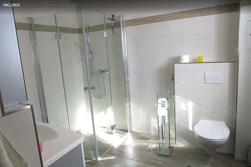 Modernes Badezimmer mit stilvollem Design und transparenter Duschtür.