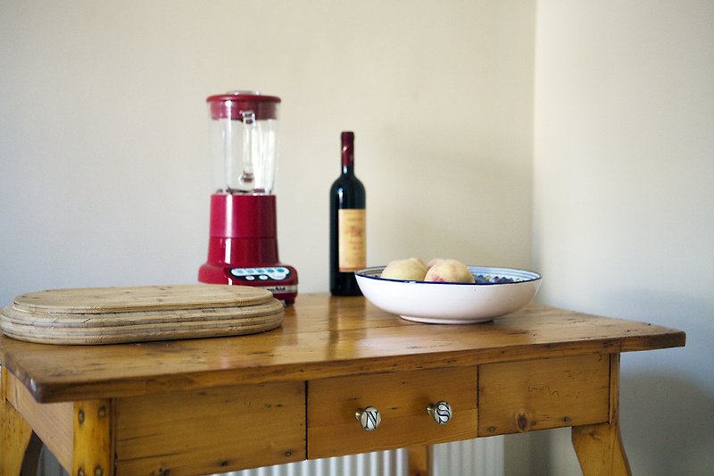 Elegante Tischdekoration mit Weinflasche, Geschirr und Früchten.