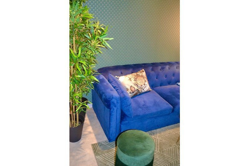 Gemütliches Wohnzimmer mit Holzmöbeln, blauen Akzenten und blühenden Pflanzen.