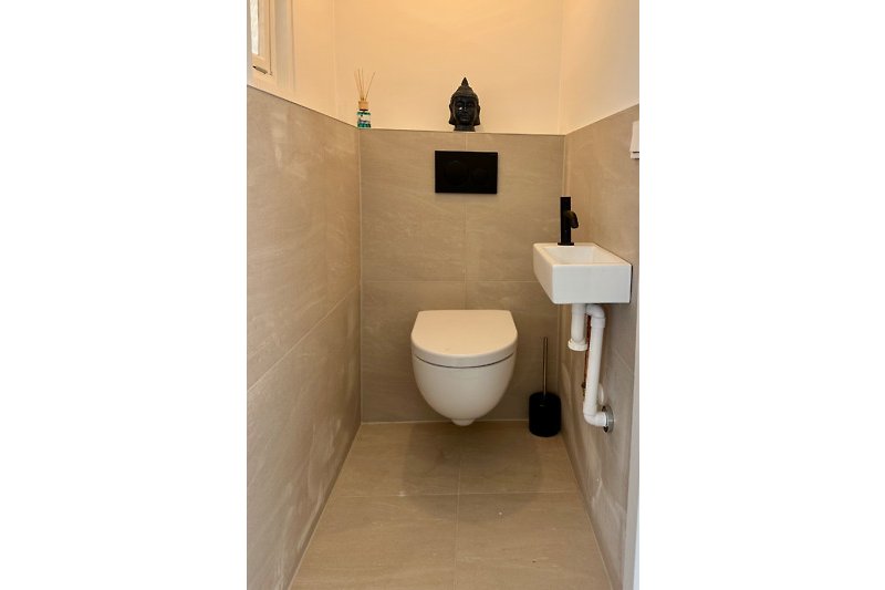Gemütliches Badezimmer mit lila Toilettenbrille und Fliesen.