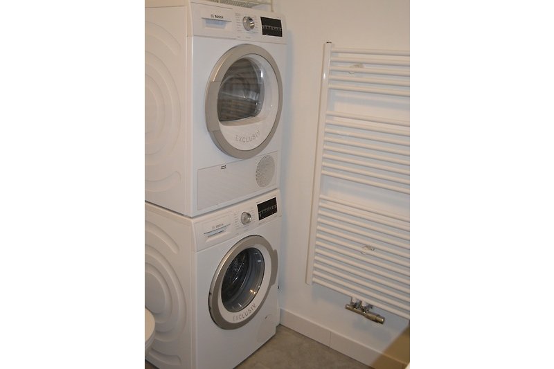 Gemütliche Waschküche mit modernen Geräten und Holzboden.