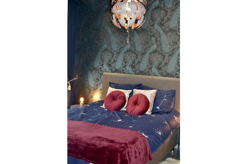 Gemütliches Schlafzimmer mit stilvoller Beleuchtung und gemusterten Kissen.
