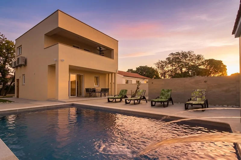Großer Pool im gepflegten Innenhof einer exklusiven Villa bei Sonnenuntergang.