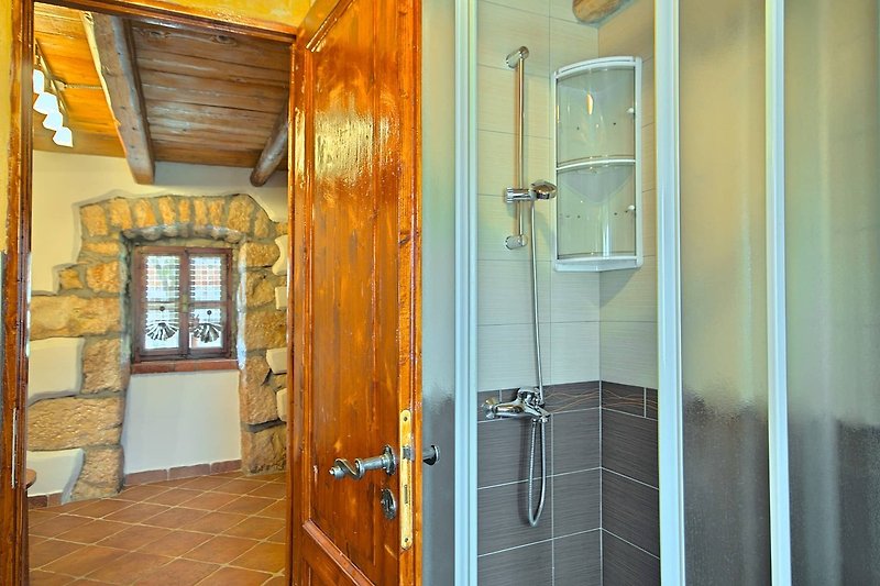 Moderne Badezimmer mit Glasdusche und Holztür.