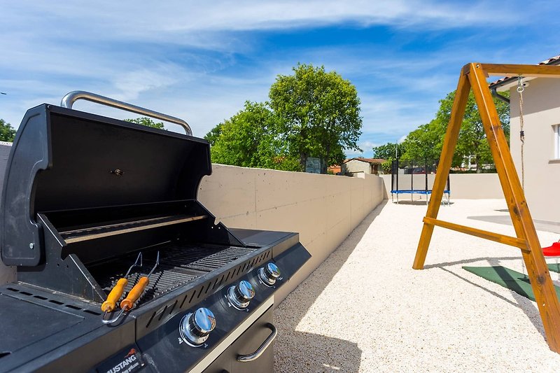 A picturesque property with a gas stove, outdoor grill, and luxury vehicle.