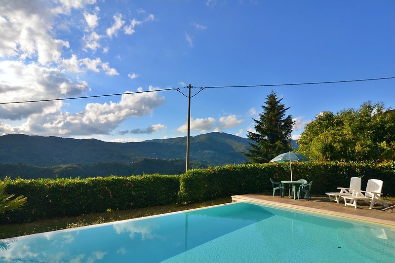 Schwimmbad mit Bergblick und Sonnenschirmen.