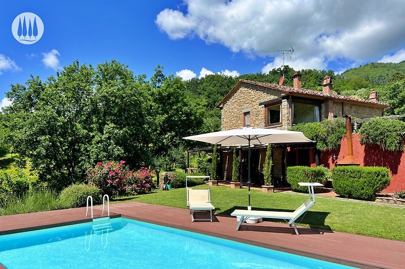 Haus mit Pool, Garten und Bergblick.