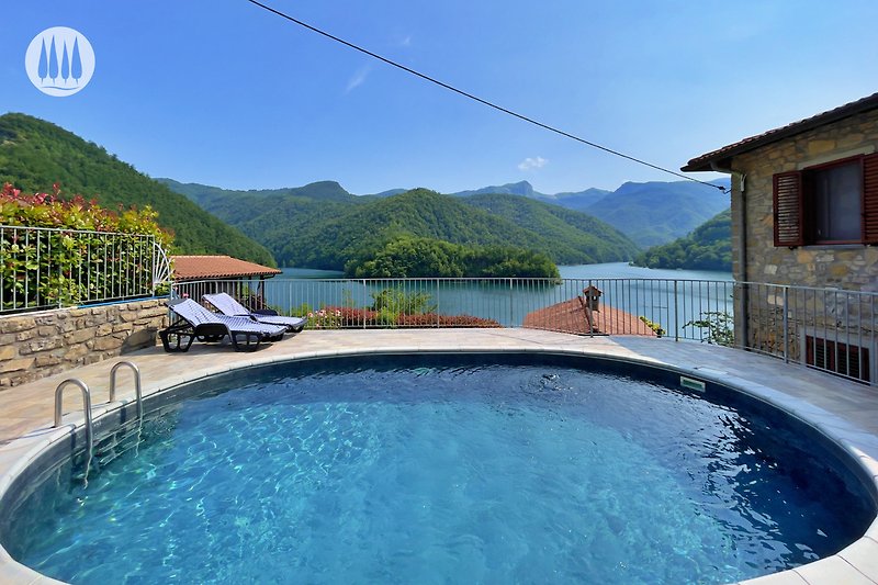 Ein blauer Swimmingpool mit Blick auf Berge und Natur. Perfekt für einen erholsamen Urlaub!