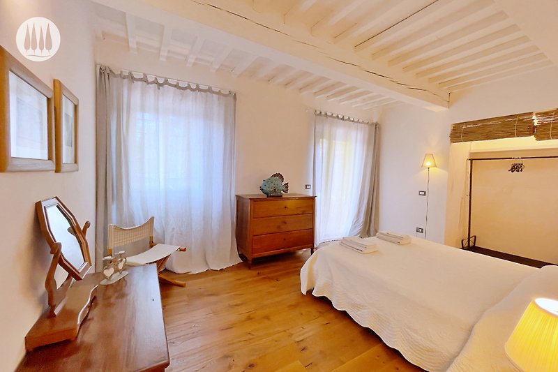 Schlafzimmer mit Holzmöbeln, Bett, Vorhängen und Lampen.