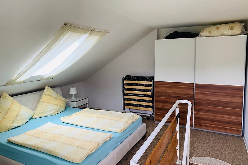 Das Schlafzimmer mit Kleiderschrank, Balkon und Zustellbett.