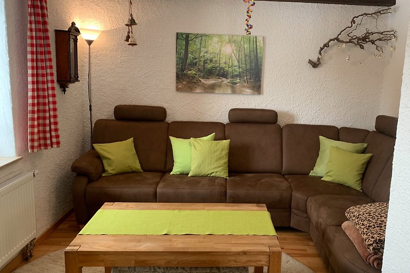 Gemütliches Wohnzimmer mit bequemen Möbeln, Holzboden und grünen Pflanzen.