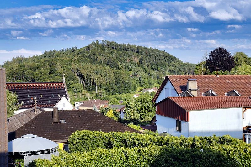 Schönes Haus in den Bergen mit grüner Landschaft und blauem Himmel.