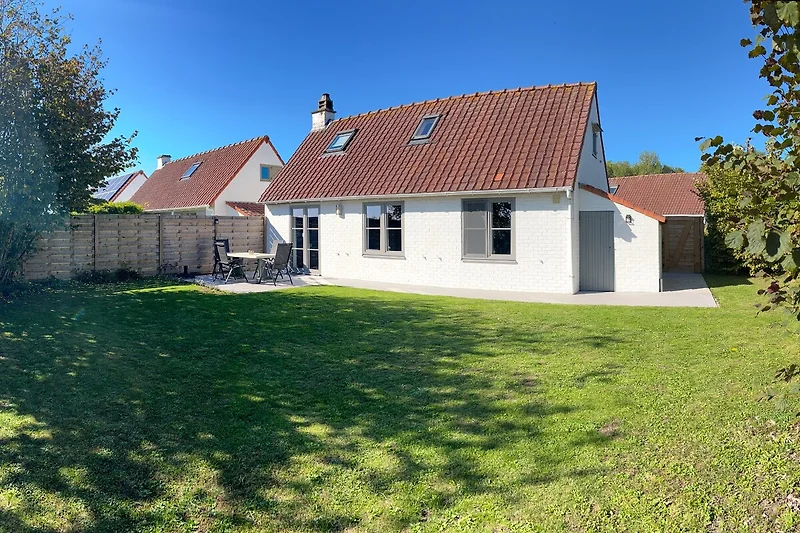 Bauernhaus mit rotem Dach in grüner Lage.