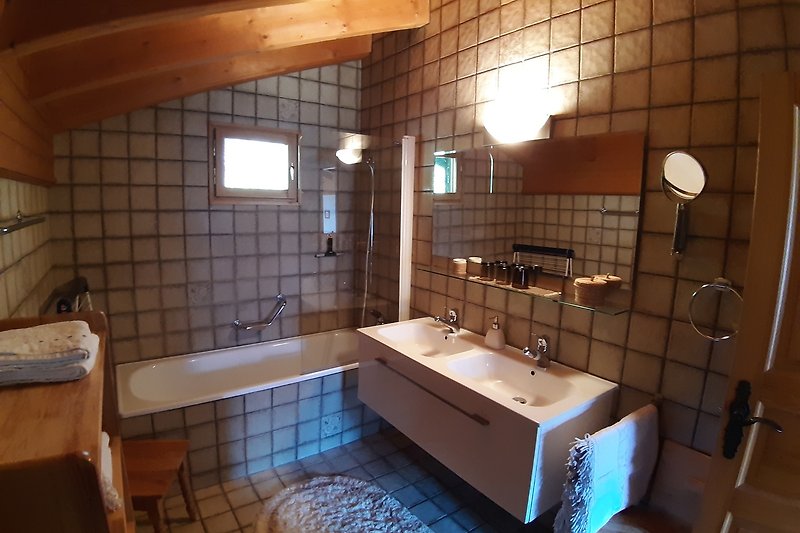 Badezimmer mit grossem Spiegel, Badewanne und Toilette