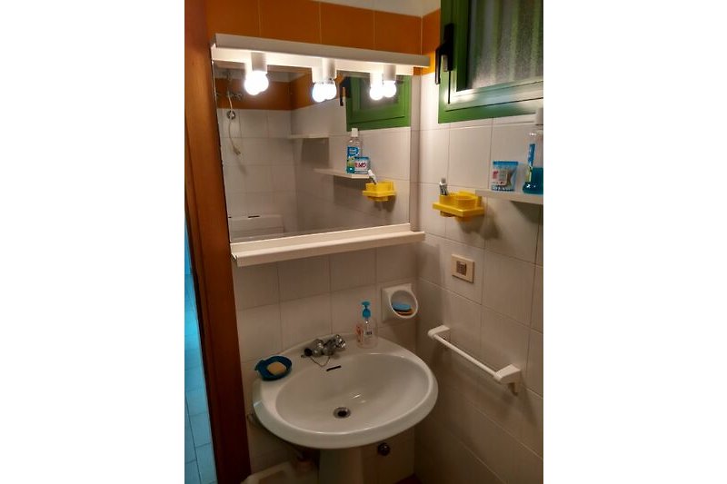 Badezimmer mit Waschbecken, Spiegel und lila Akzenten.