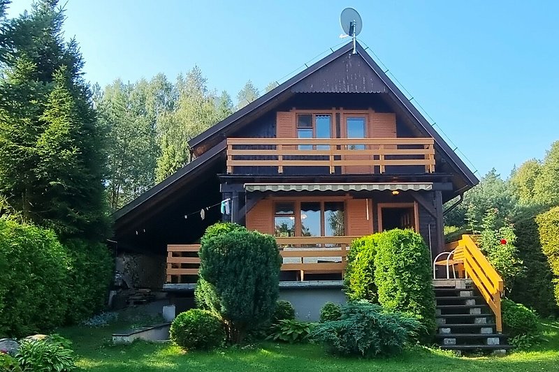 Charmantes Holzhaus mit Garten, Bäumen und Veranda.