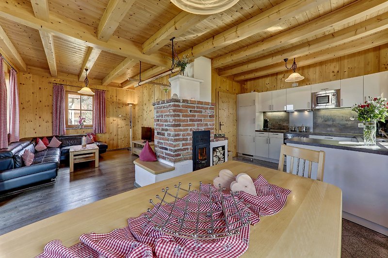 Gemütliches Wohnzimmer mit Holzmöbeln, Kachelofen, Küche und stilvoller Einrichtung.