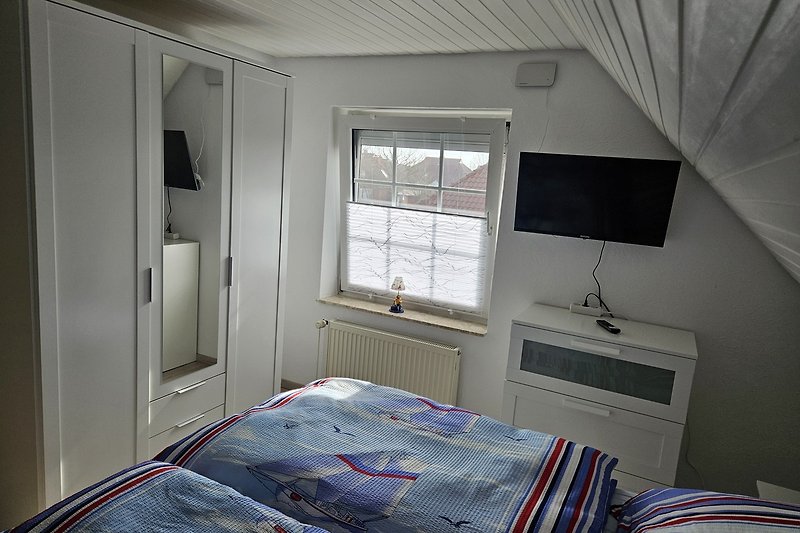 Stilvolles Schlafzimmer mit Fernseher und gemütlichem Bett.
