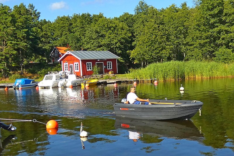 Boot am See mit Bäumen und blauem Himmel im Hintergrund.