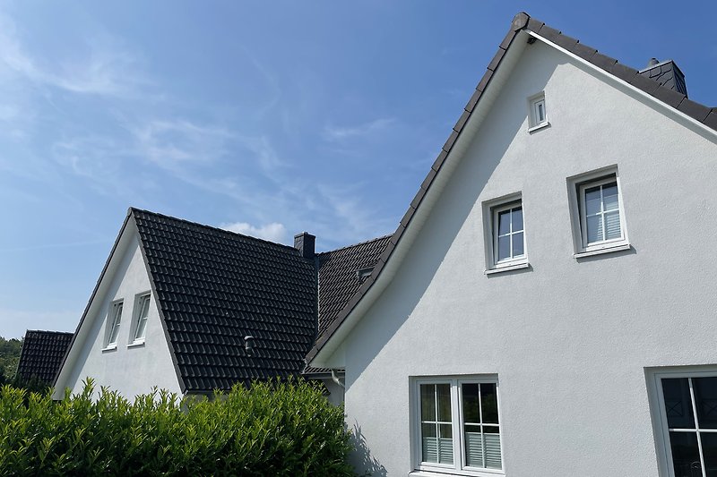 Gemütliches Landhaus mit Holzfassade und Sprossenfenstern, umgeben von Grün.