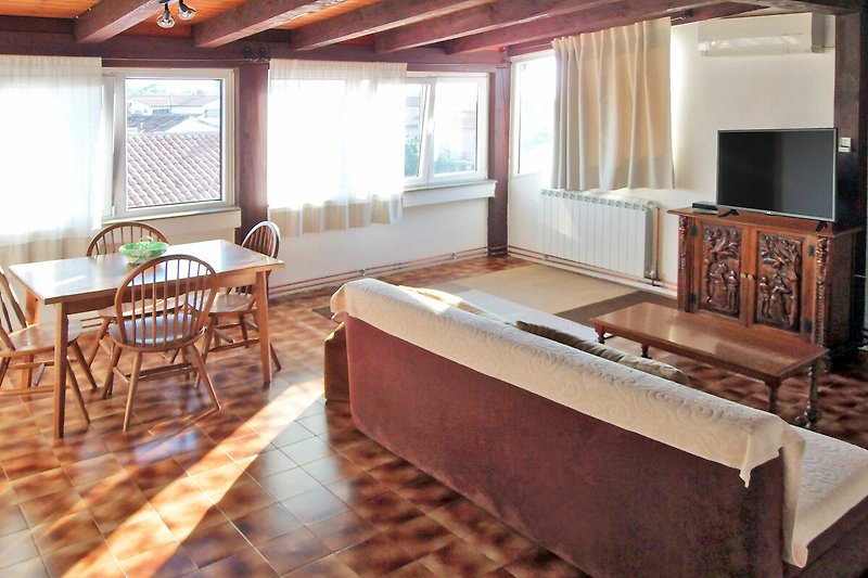 Gemütliches Wohnzimmer mit Holzboden und großen Fenstern.