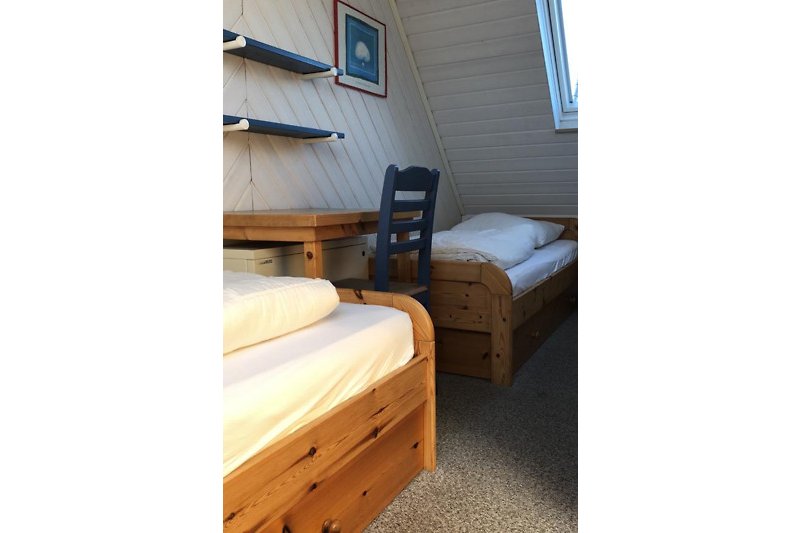 Gemütliches Schlafzimmer mit Holzmöbeln und blauen Bettwäsche.